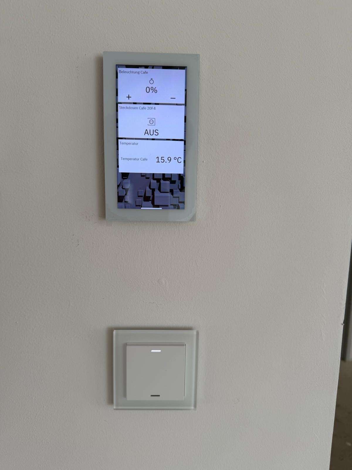 Dotykový ovládací panel vykurovania a vetrania osadený na stene, pod ním vypínač